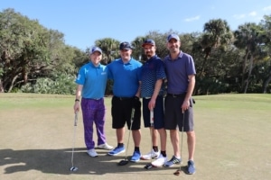 Four male golfers smiling and standing in a row participating in the STARS of the Spectrum Golf program (Flutie Foundation for Autism)