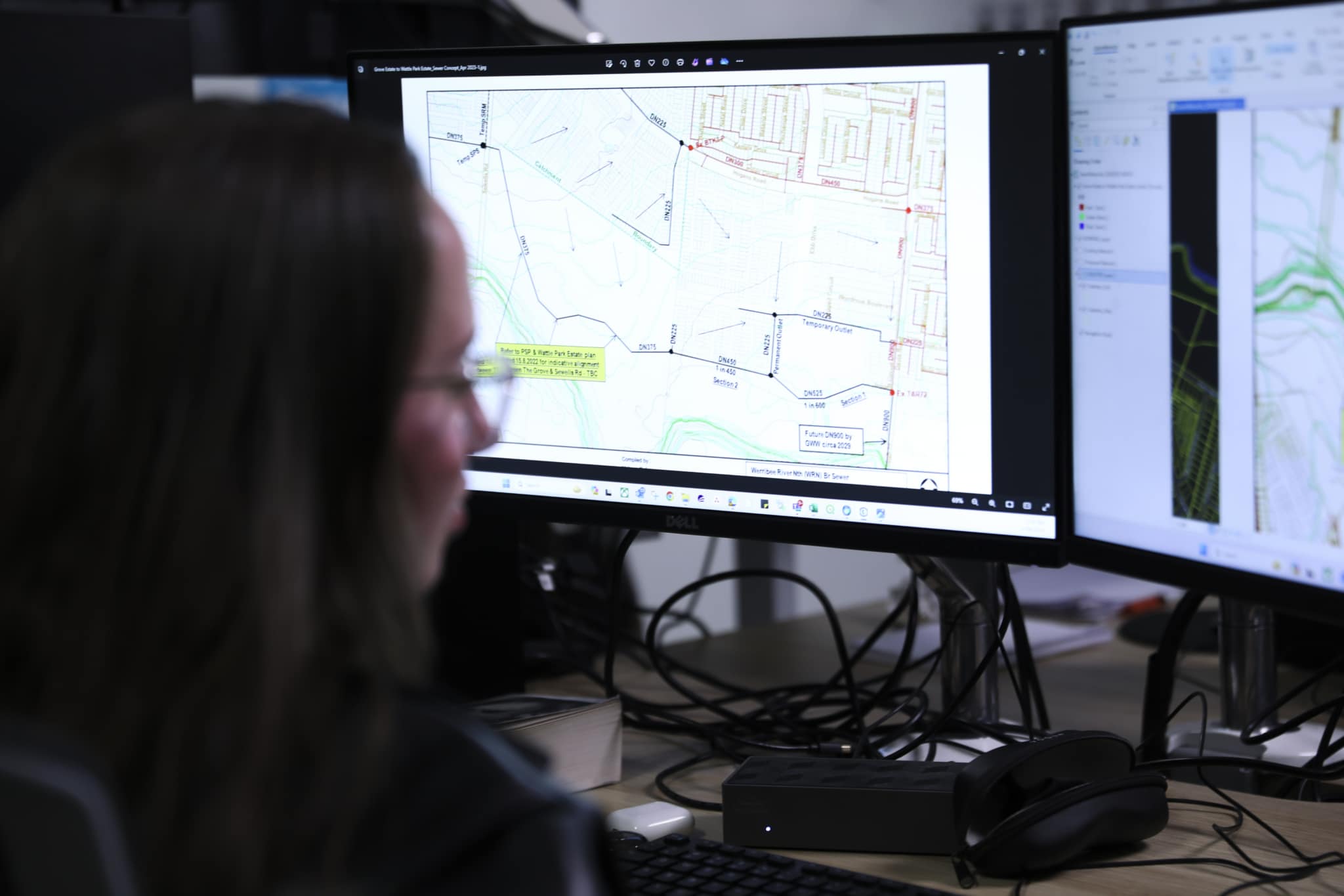 Image depicting an employee at Australian Spatial Analytics (ASA) working on a dual computer monitor work station.
